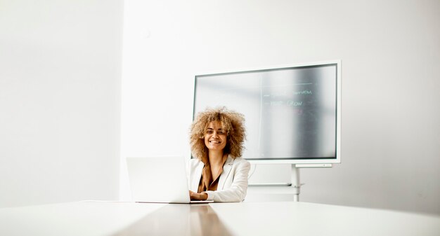 Joven empresaria afroamericana sentado y trabajando en la computadora portátil en la oficina moderna