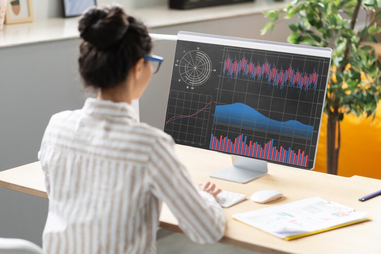 Foto joven empresaria analizando estadísticas en la pantalla de la computadora trabajando con gráficos financieros y gráficos en línea en la oficina