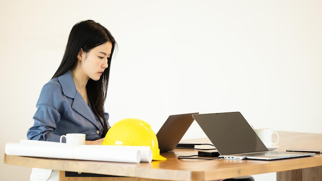 Joven empresaria asiática arquitectura en la oficina trabajando con computadora portátil Joven arquitecta asiática trabajando en proyecto Mujer de arquitectura trabajando portátil en el espacio de trabajo