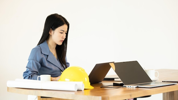 Joven empresaria asiática arquitectura en la oficina trabajando con computadora portátil Joven arquitecta asiática trabajando en proyecto Mujer de arquitectura trabajando portátil en el espacio de trabajo