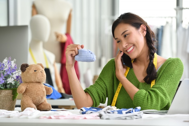 Joven empresaria asiática / diseñadora de moda para ropa de bebé trabajando en estudio