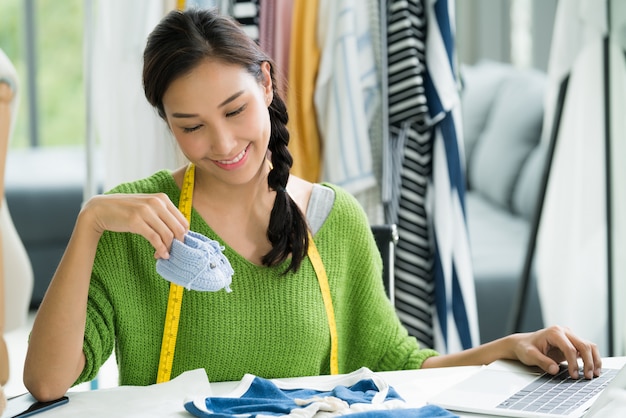 Joven empresaria asiática / diseñadora de moda para ropa de bebé trabajando en estudio