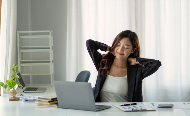 Joven empresaria asiática estirando los brazos levantados relajándose en la oficinaxA
