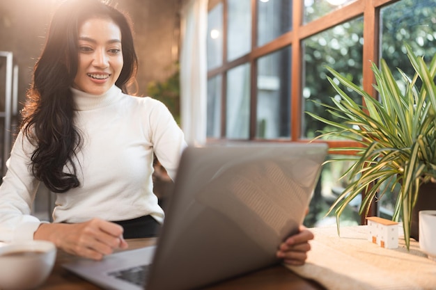 Joven empresaria asiática independiente que usa una computadora portátil para trabajar en el ciberespacio en línea en el lugar de trabajo mujer en un feliz estilo de vida moderno mujer de negocios que trabaja en tecnología de oficina remota digital