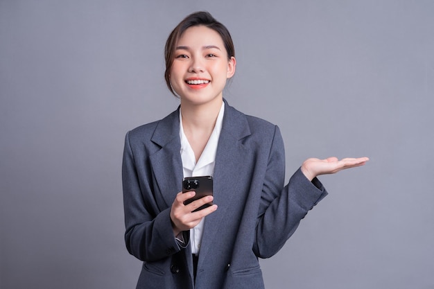 Joven empresaria asiática con smartphone en fondo gris