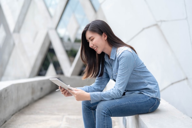 Joven empresaria asiática trabajando en línea en tableta y regocijo