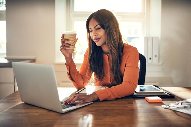 Joven empresaria bebiendo café y trabajando en su oficina en casa