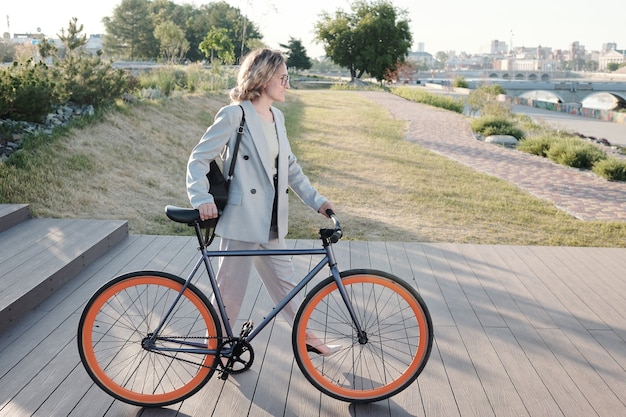 Joven empresaria con bicicleta hacia la carretera