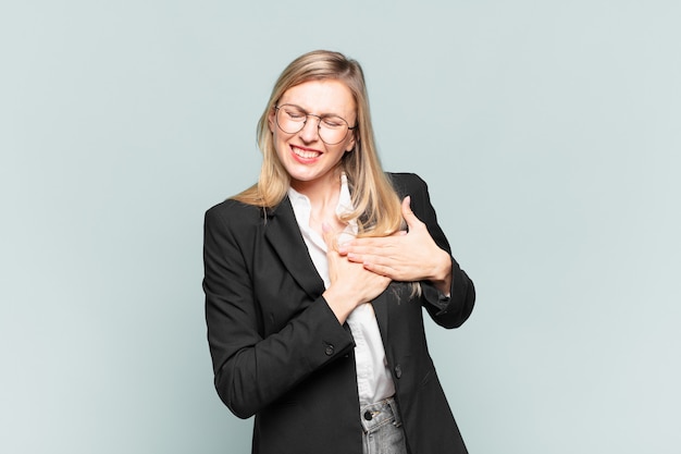 Foto joven empresaria bonita que parece triste, herida y con el corazón roto, sosteniendo ambas manos cerca del corazón, llorando y sintiéndose deprimida