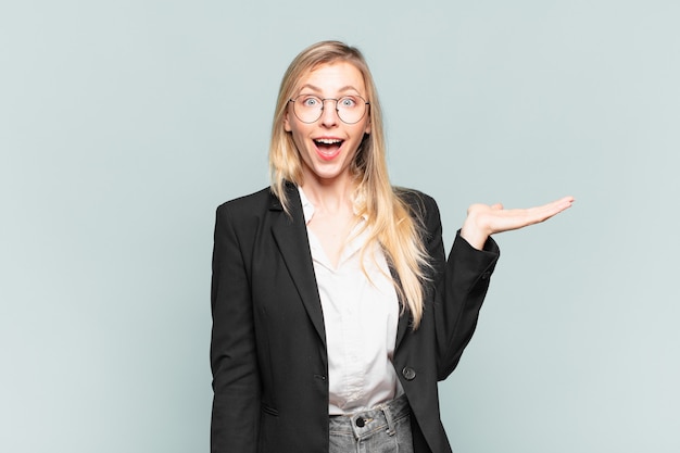 Joven empresaria bonita que se siente feliz, sorprendida y alegre, sonriendo con actitud positiva, dándose cuenta de una solución o idea