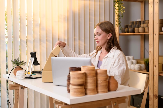 Una joven empresaria bonita revisando y empaquetando productos artesanales