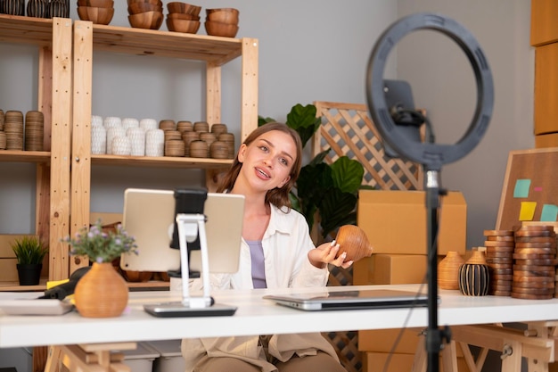 Una joven empresaria bonita transmite en vivo para vender productos artesanales a los clientes en su tienda