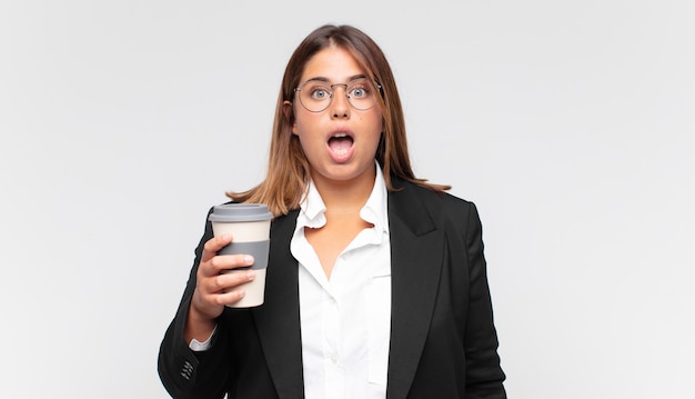 Joven empresaria con un café mirando muy conmocionado o sorprendido