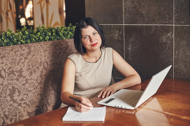 Joven empresaria caucásica con portátil y portátil. Mujer en cafe