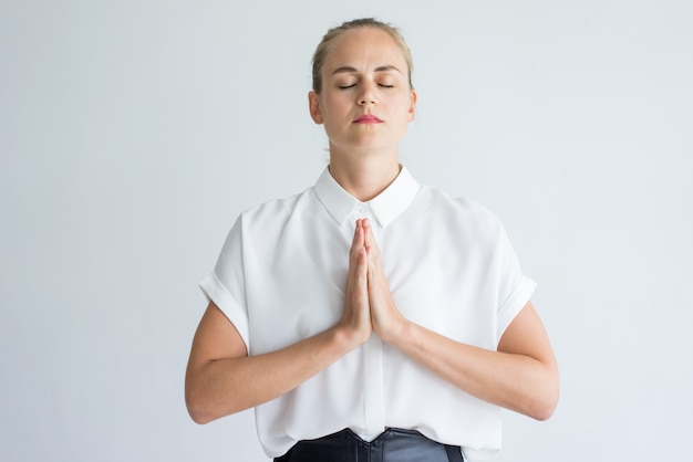 joven empresaria caucásica vistiendo camisa blanca meditando