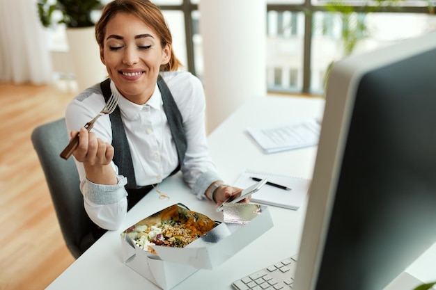 Joven empresaria comiendo alimentos saludables en el almuerzo en la oficina