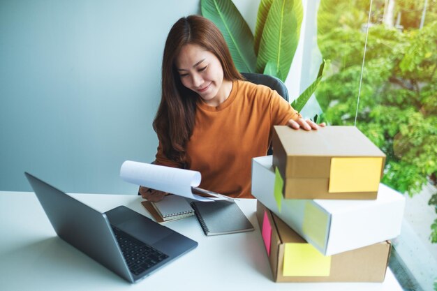 Joven empresaria comprobando pedidos del cliente para compras en línea y concepto de entrega