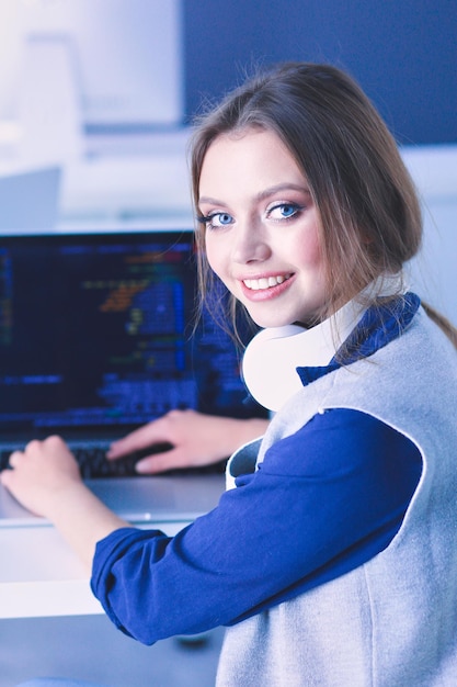 Foto joven empresaria confiada que trabaja en el escritorio de oficina y escribiendo con una computadora portátil