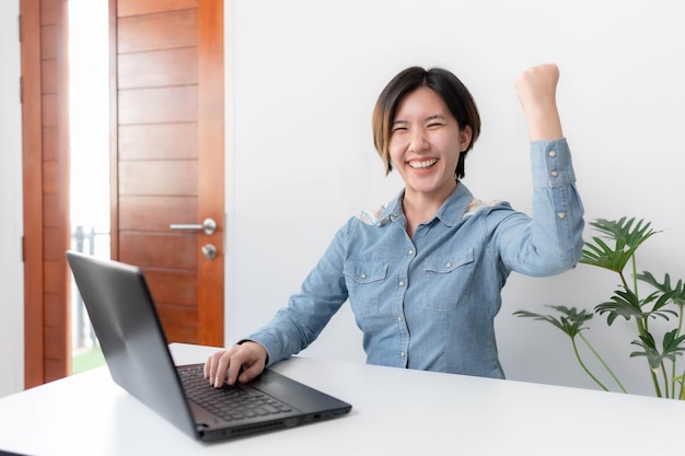 Una joven empresaria está muy feliz después de revisar su correo electrónico a través de su computadora portátil