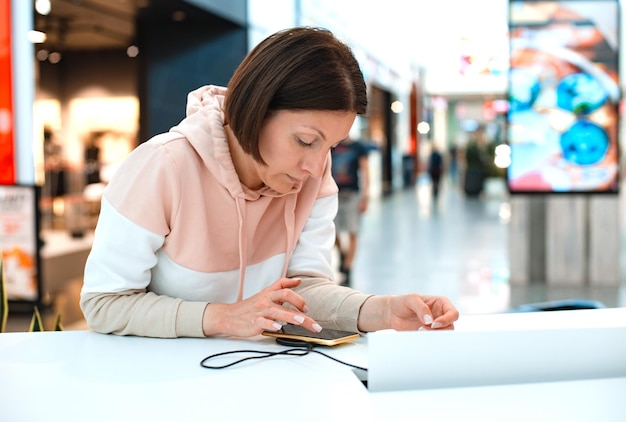 La joven empresaria está trabajando con su teléfono mientras carga la batería que sostiene el teléfono inteligente w