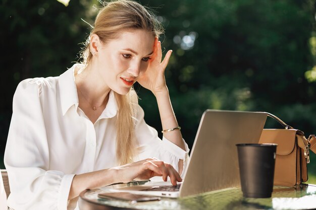 Joven empresaria exitosa usando laptop para trabajar al aire libre