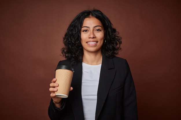 Una joven empresaria felizmente sostiene un café togo listo para un día exitoso