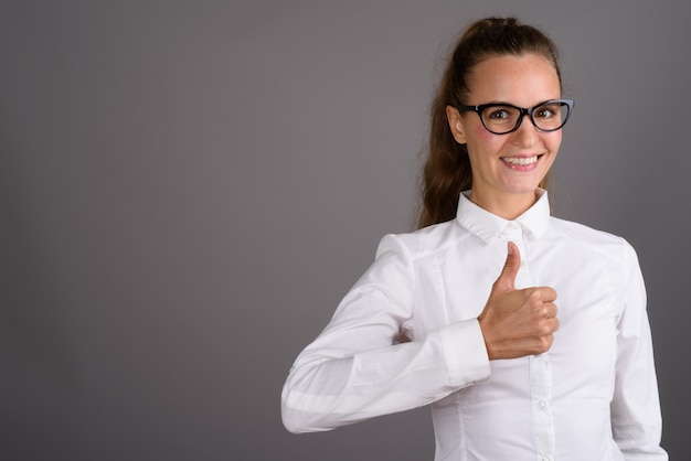 Joven empresaria hermosa contra el fondo gris