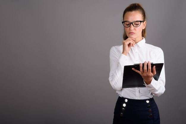 Joven empresaria hermosa contra el fondo gris