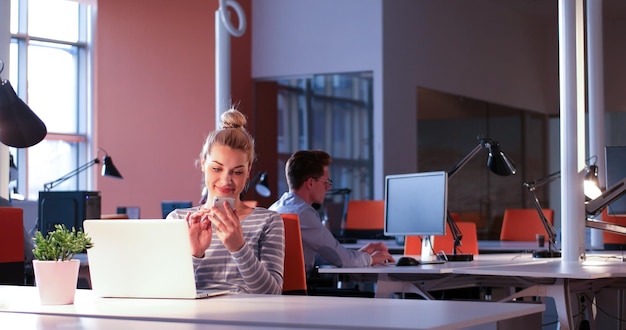 Joven empresaria independiente que trabaja con una computadora portátil en el espacio de coworking