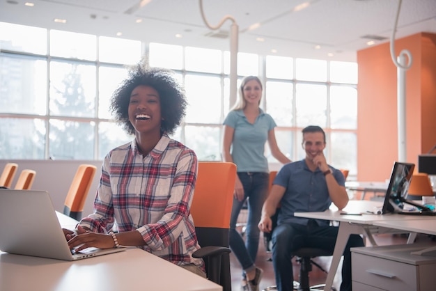 joven empresaria informal afroamericana sonriente que trabaja en la oficina con colegas en el fondo