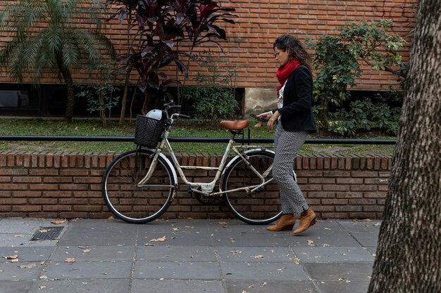 Joven empresaria latinoamericana camina hacia su bicicleta antigua