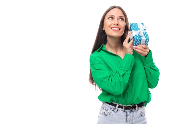 La joven empresaria morena de ojos marrones con una camisa verde tiene un regalo para las vacaciones