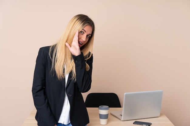 Joven empresaria en una oficina susurrando algo