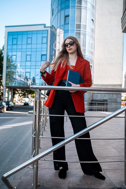 Joven empresaria profesional en traje de pie cerca del edificio de oficinas con los brazos cruzados