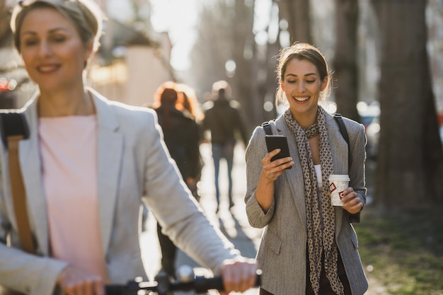 Una joven empresaria que usa un teléfono inteligente mientras va a trabajar.