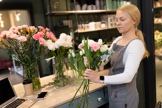 Joven empresaria entre ramos de flores en una floristería