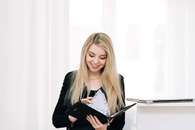 Joven empresaria rubia sosteniendo un cuaderno