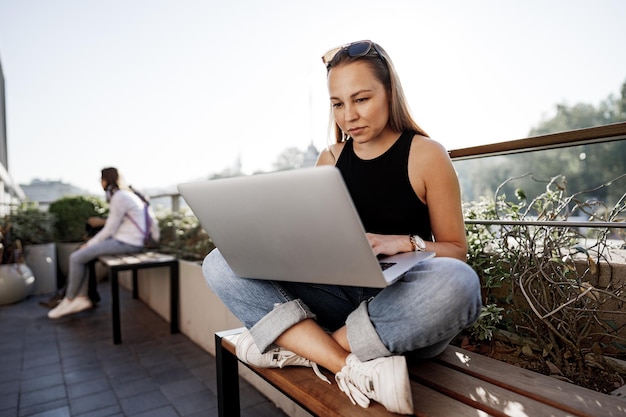 Joven empresaria rubia usando una computadora portátil trabajando en la terraza en estambul