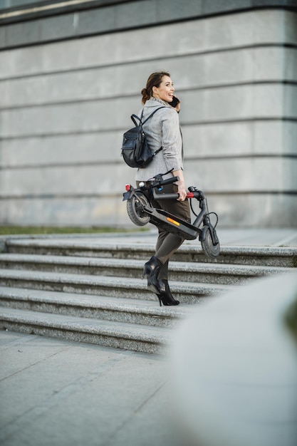 Una joven empresaria con un scooter eléctrico que va a trabajar.