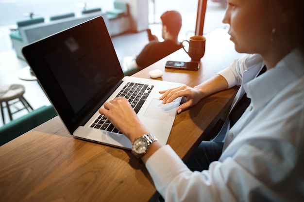 Joven empresaria sentada en un café y trabajando con una laptop