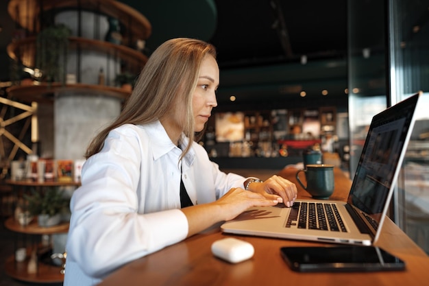 Joven empresaria sentada en un café y trabajando con una laptop