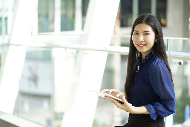 Foto joven empresaria sentado y usando tableta al aire libre. asia trabajadora sentada con digi