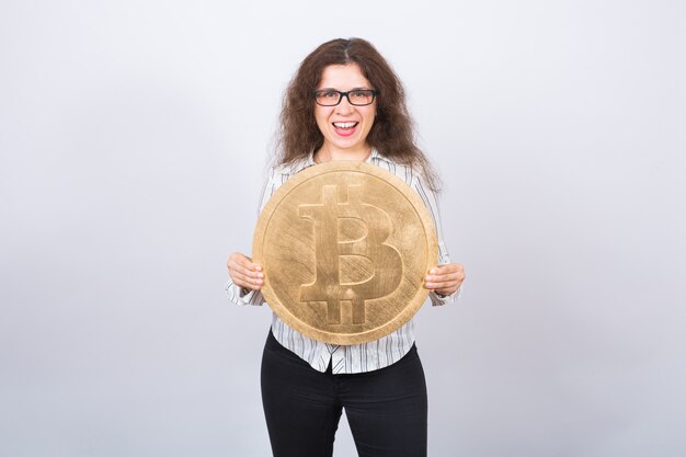 Joven empresaria sosteniendo un bitcoin dorado