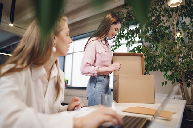 Joven empresaria sosteniendo una caja de pertenencias personales a punto de dejar la oficina después de dejar el trabajo