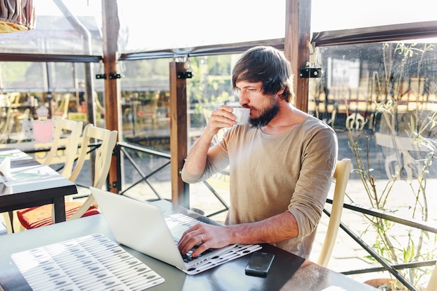 Foto joven empresaria tomando café y usando tableta en café
