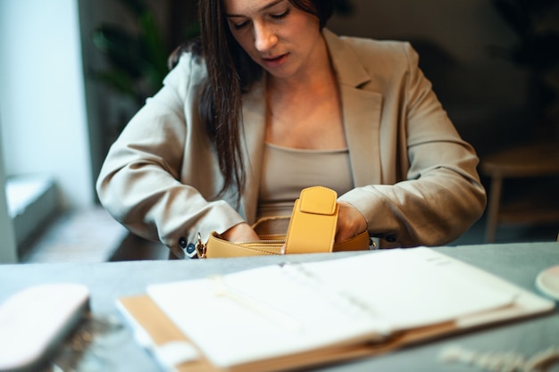 Joven empresaria en traje abriendo una bolsa de cuero de color naranja