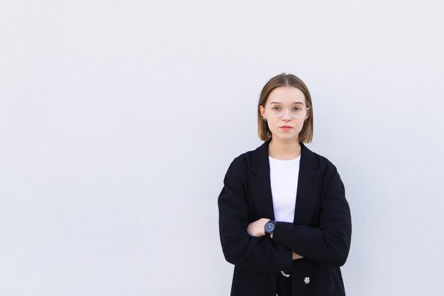 Foto joven empresaria con un traje y gafas en blanco con una mirada seria.