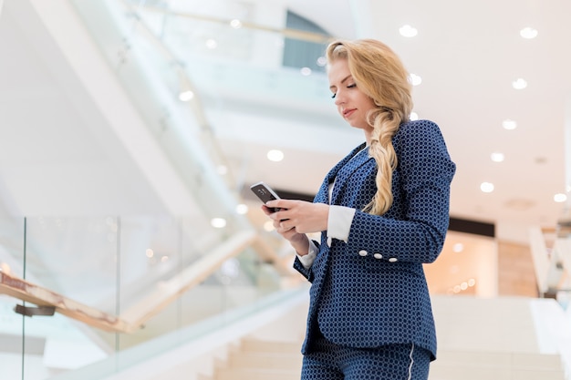 Joven empresaria usando su teléfono inteligente para navegar por el contenido web y enviar mensajes