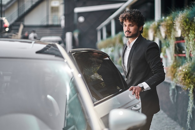 Joven empresario abre su coche.