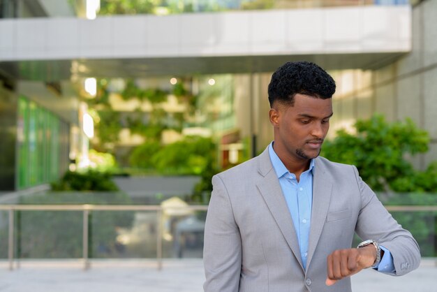 Joven empresario africano al aire libre comprobando el tiempo del reloj